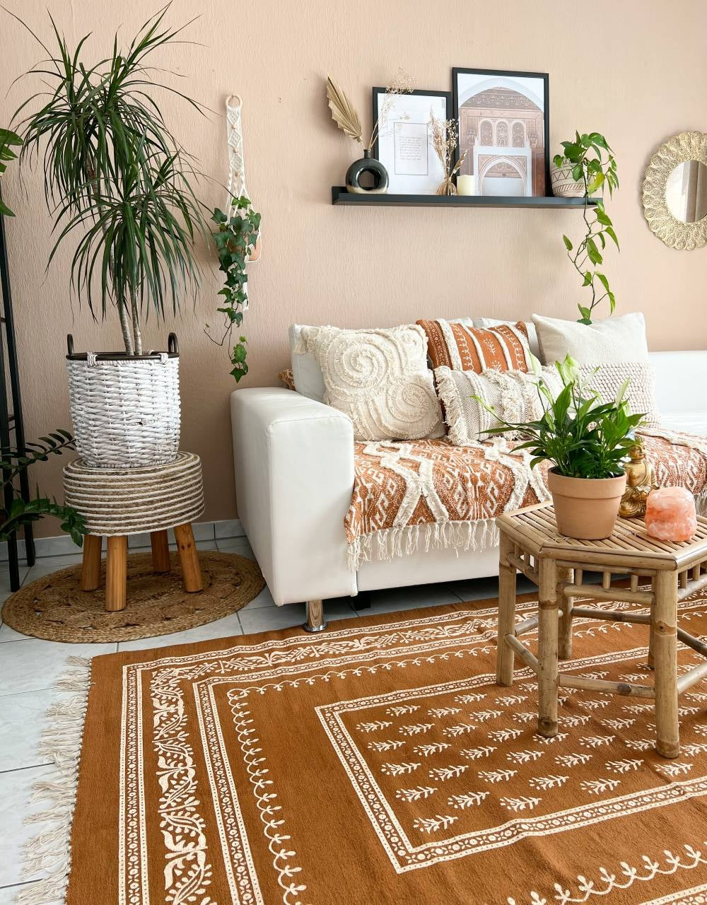 Wide view of a globally-inspired living room with the Nidhi ochre cushion on a white sofa, matching an ochre and white hand-block printed area rug.