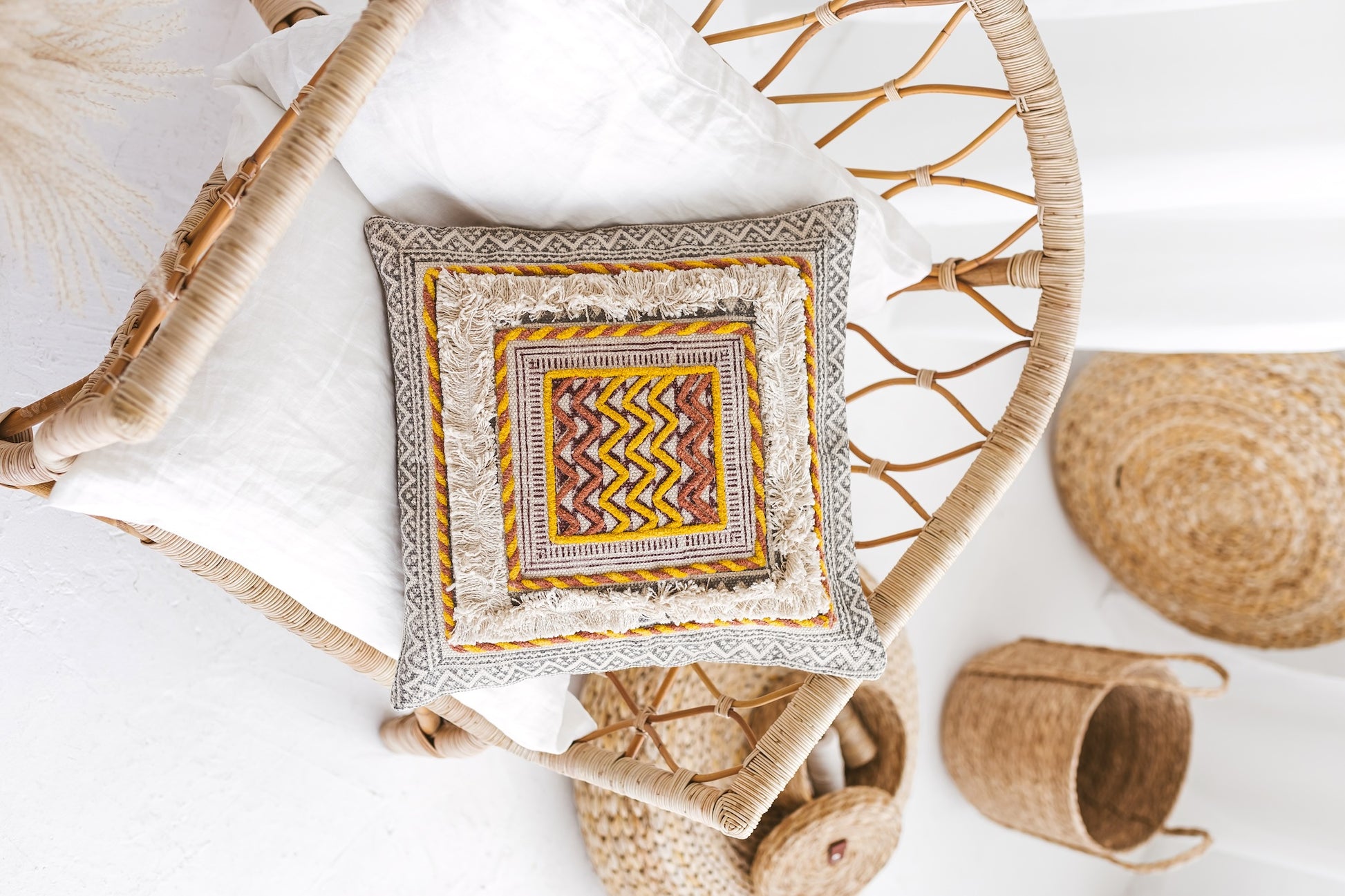 Studio close-up of the Bodhi cushion highlighting the intricate 3D chain stitching, raised french knots, and plush multi-colored corner tassels.