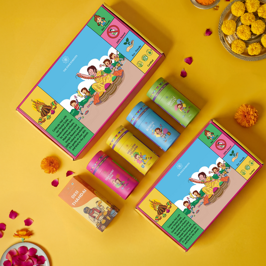 Complete Holi Gift Hamper flatlay featuring The Four Pursuits herbal gulal box, color canisters (Blue, Yellow, Pink ,Green), Thandai mix, and traditional sweets. The perfect premium Holi gift set.